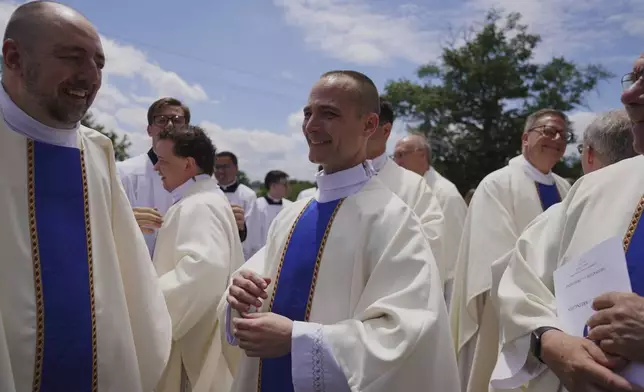 The Revs. Andrew Lewandowski, left, and Mike Sampson, center, stand among fellow priests after their ordination Mass at the Cathedral of Saint Thomas More in Arlington, Va., on Saturday, June 7, 2025. (AP Photo/Jessie Wardarski)
