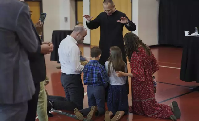 The Rev. Mike Sampson blesses the Hilgert family during a reception after his first Mass, given at St. Charles Borromeo Catholic Church in Arlington, Va., on Sunday, June 8, 2025. (AP Photo/Jessie Wardarski)