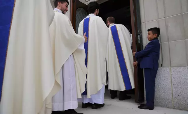 Priests greet a young usher while entering the Cathedral of Saint Thomas More for the ordination of 12 priests in Arlington, Va., on Saturday, June 7, 2025. (AP Photo/Jessie Wardarski)