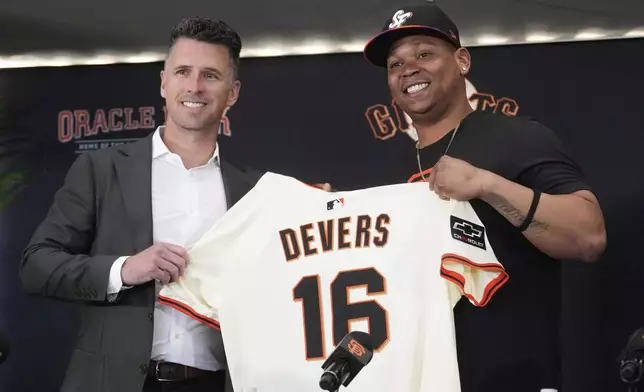 San Francisco Giants' Rafael Devers, right, poses for photos with President of Baseball Operations Buster Posey at a news conference before a baseball game between the Giants and the Cleveland Guardians in San Francisco, Tuesday, June 17, 2025. (AP Photo/Jeff Chiu)