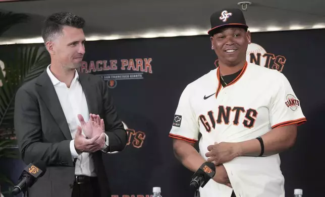 San Francisco Giants' Rafael Devers, right, smiles next to President of Baseball Operations Buster Posey at a news conference before a baseball game between the Giants and the Cleveland Guardians in San Francisco, Tuesday, June 17, 2025. (AP Photo/Jeff Chiu)