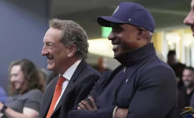 San Francisco Giants President &amp; Chief Executive Officer Larry Baer, left, and former player Barry Bonds listen as Rafael Devers speaks at a news conference before a baseball game between the Giants and the Cleveland Guardians in San Francisco, Tuesday, June 17, 2025. (AP Photo/Jeff Chiu)