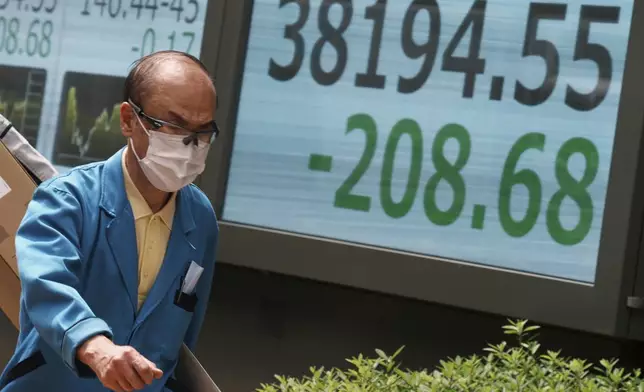 A person walks in front of an electronic stock board showing Japan's Nikkei index at a securities firm Monday, June 23, 2025, in Tokyo. (AP Photo/Eugene Hoshiko)