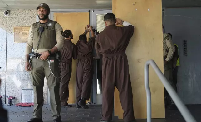 Inmates board up the U.S. Department of Justice Federal Bureau of Prisons during a protest on Friday, June 6, 2025, in Los Angeles. (AP Photo/Jae C. Hong)