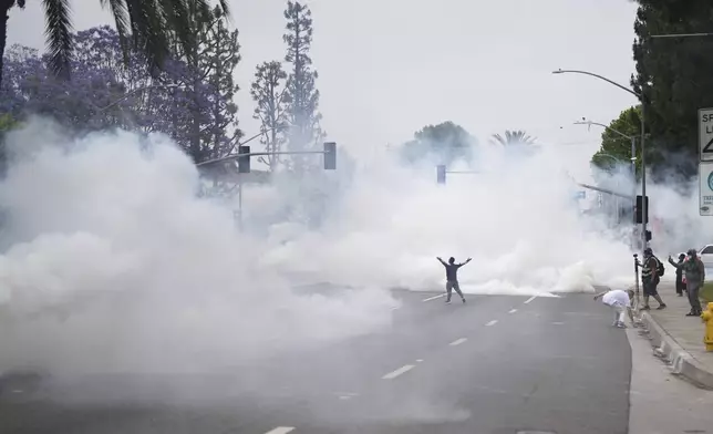 Smoke fills the street as protesters confront Border Patrol personnel during a demonstration over the dozens detained in an operation by federal immigration authorities a day earlier in Paramount section of Los Angeles Saturday, June 7, 2025. (AP Photo/Eric Thayer)