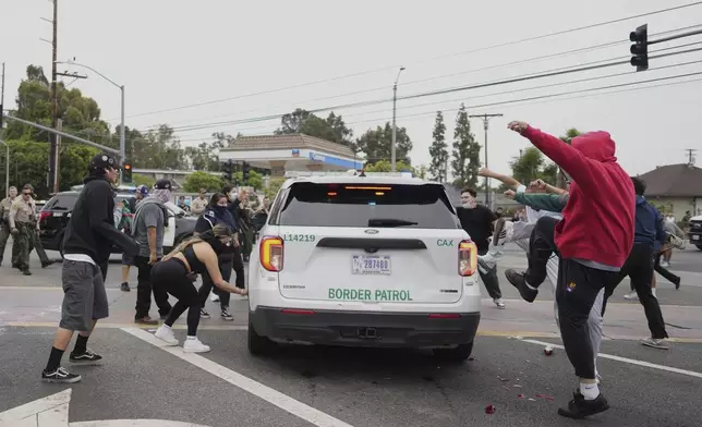 Protesters kick the side of a Border Patrol vehicle during a demonstration over the dozens detained in an operation by federal immigration authorities a day earlier in Paramount section of Los Angeles Saturday, June 7, 2025. (AP Photo/Eric Thayer)
