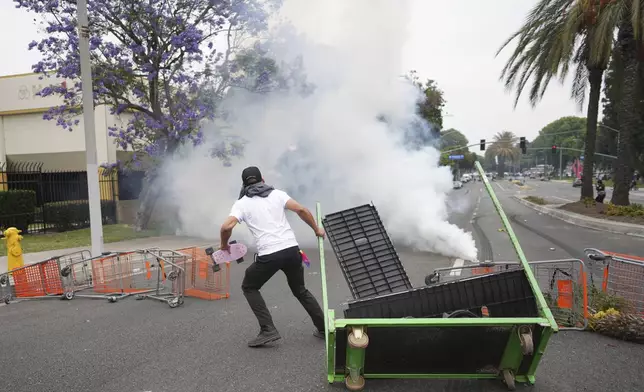 A protester looks on as Border Patrol personnel in riot gear and gas masks stood guard outside an industrial park in the Paramount section of Los Angeles, Saturday, June 7, 2025. (AP Photo/Eric Thayer)