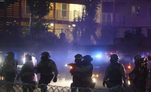 Law enforcement stand during a protest in Compton, Calif., Saturday, June 7, 2025, after federal immigration authorities conducted operations. (AP Photo/Ethan Swope)
