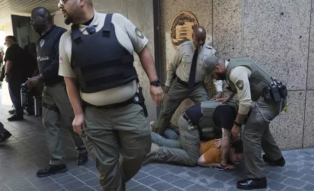 Law enforcement detain a protester at the U.S. Department of Justice Federal Bureau of Prisons after federal immigration authorities conducted an operation on Friday, June 6, 2025, in Los Angeles. (AP Photo/Jae C. Hong)