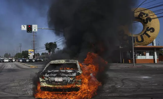 A car burns during a protest in Compton, Calif., Saturday, June 7, 2025, after federal immigration authorities conducted operations. (AP Photo/Eric Thayer)