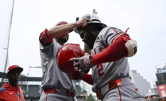 Los Angeles Angels' Luis Rengifo (2) has a firefighters helmet placed on his head by Nolan Schanuel after hitting a solo home run against Baltimore Orioles pitcher Keegan Akin during the sixth inning of a baseball game in Baltimore, Saturday, June 14, 2025. (AP Photo/Terrance Williams)