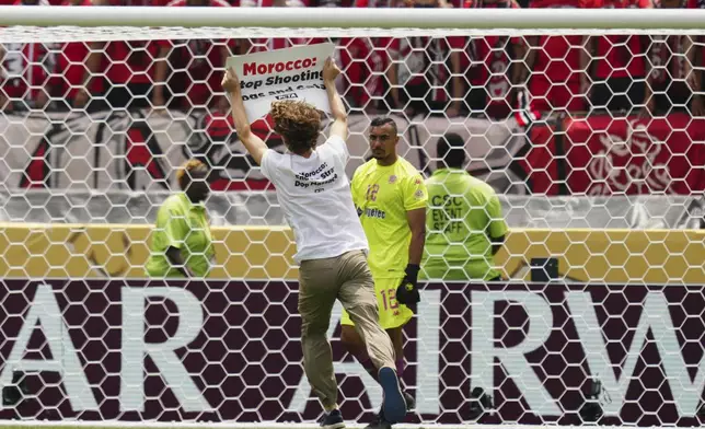 A protester runs on the pitch during the Club World Cup group G soccer match between Manchester City and Wydad AC in Philadelphia, Wednesday, June 18, 2025. (AP Photo/Derik Hamilton)