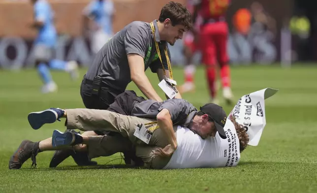 A pitch invader is taken down by security during the Club World Cup group G soccer match between Manchester City and Wydad AC in Philadelphia, Wednesday, June 18, 2025. (AP Photo/Chris Szagola)