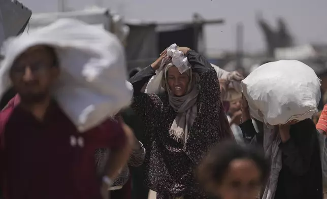 Palestinians carry bags containing food and humanitarian aid packages delivered by the Gaza Humanitarian Foundation, a U.S.-backed organization, in Rafah, southern Gaza Strip, Monday, June 16, 2025. (AP Photo/Abdel Kareem Hana)