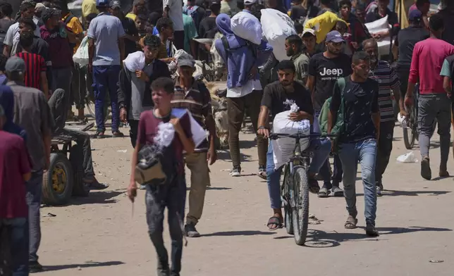 Palestinians carry bags containing food and humanitarian aid packages delivered by the Gaza Humanitarian Foundation, a U.S.-backed organization, in Rafah, southern Gaza Strip, Sunday, June 15, 2025. (AP Photo/Abdel Kareem Hana)