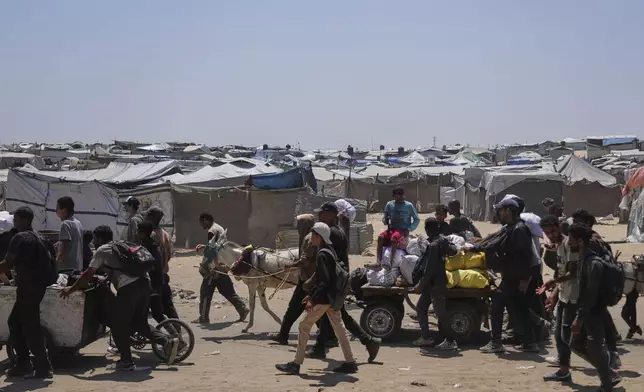 Palestinians carry bags containing food and humanitarian aid packages delivered by the Gaza Humanitarian Foundation, a U.S.-backed organization, in Rafah, southern Gaza Strip, Monday, June 16, 2025. (AP Photo/Abdel Kareem Hana)