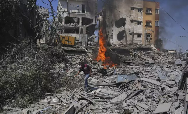 A Palestinian man walks across the rubble of a building destroyed by an Israeli strike in Deir al-Balah, central Gaza Strip, Monday, June 16, 2025. (AP Photo/Abdel Kareem Hana)