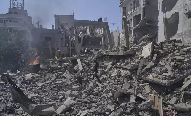 A Palestinian man walks across the rubble of a building destroyed by an Israeli strike in Deir al-Balah, central Gaza Strip, Monday, June 16, 2025. (AP Photo/Abdel Kareem Hana)