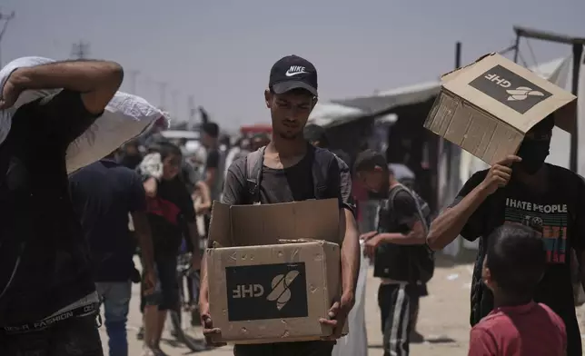 Palestinians carry bags and boxes containing food and humanitarian aid packages delivered by the Gaza Humanitarian Foundation, a U.S.-backed organization, in Rafah, southern Gaza Strip, Monday, June 16, 2025. (AP Photo/Abdel Kareem Hana)