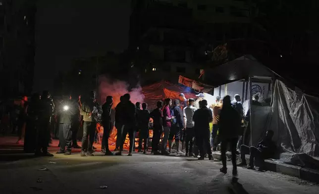 Palestinians line up to buy dinner at a food stand near the beachfront at a tent camp for displaced people in the Gaza City port, Saturday, June 14, 2025. (AP Photo/Jehad Alshrafi)
