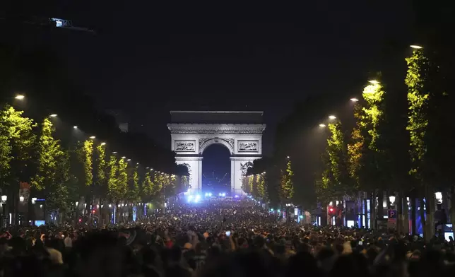 Soccer fans celebrate PSG's victory on the Champs-Elysees avenue, with the Arc de Triomphe in background, after the Champions League final soccer match between Paris Saint-Germain and Inter Milan, Sunday, June 1, 2025 in Paris. (AP Photo/Aurelien Morissard)