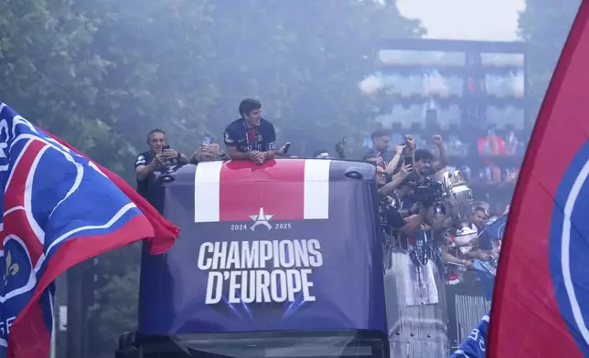 PSG players present the trophy to supporters during a parade on the Champs-Elysees avenue after the team won the Champions League final soccer match between Paris Saint-Germain and Inter Milan Sunday, June 1, 2025 in Paris. (AP Photo/Thibault Camus)