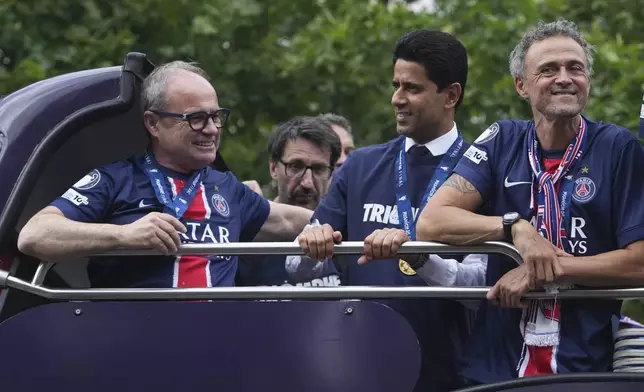 PSG's head coach Luis Enrique, right, and PSG owner Nasser bin Ghanim Al-Khelaifi, center, attend a parade on the Champs-Elysees avenue after the team won the Champions League final soccer match between Paris Saint-Germain and Inter Milan Sunday, June 1, 2025 in Paris. (AP Photo/Thibault Camus)
