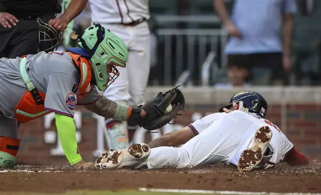 Atlanta Braves' Matt Olson, right, slides home ahead of a tag from New York Mets catcher Francisco Alvarez, left, in the fourth inning of a baseball game, Thursday, June 19, 2025, in Atlanta. (AP Photo/Colin Hubbard)