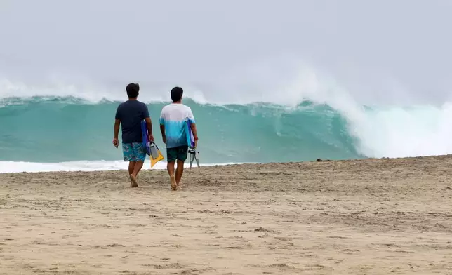 People walk on Zicatela beach prior to the arrival of Hurricane Erick in Puerto Escondido, Oaxaca state, Mexico, Wednesday, June 18, 2025. (AP Photo/Luis Alberto Cruz)