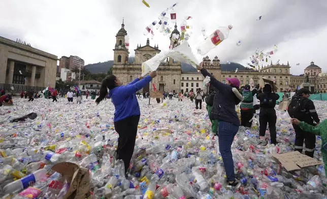 Recyclers throw plastic bottles into the air in Plaza Bolivar in Bogota, Colombia, as they protest what they consider to be too low a price paid by companies that buy recycled materials, Tuesday, June 24, 2025. (AP Photo/Fernando Vergara)