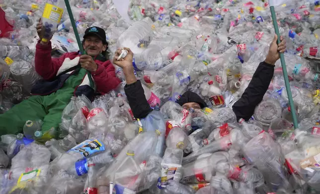 Recyclers lie on plastic bottles blanketing Plaza Bolivar in Bogota, Colombia, as part of a protest against what recyclers consider to be too low a price paid to them by companies that buy recycled materials, Tuesday, June 24, 2025. (AP Photo/Fernando Vergara)