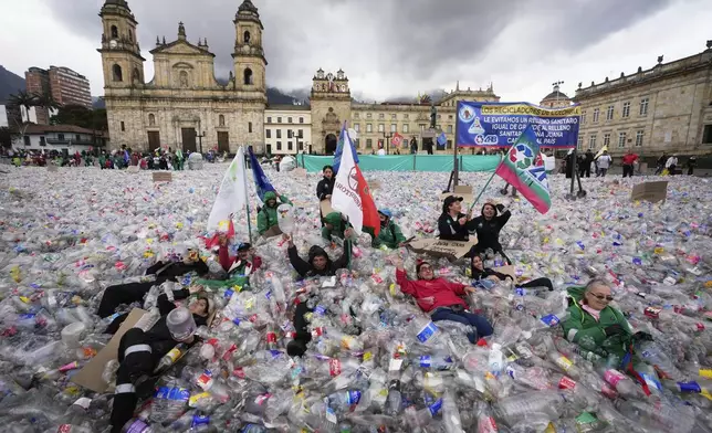 Recyclers lie on plastic bottles blanketing Plaza Bolivar in Bogota, Colombia, as part of a protest against what recyclers consider to be too low a price paid to them by companies that buy recycled materials, Tuesday, June 24, 2025. (AP Photo/Fernando Vergara)