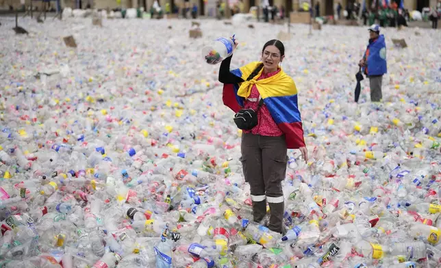 A recycler stands amid plastic bottles blanketing Plaza Bolivar in Bogota, Colombia, as part of a protest against what recyclers consider to be too low a price paid to them by companies that buy recycled materials, Tuesday, June 24, 2025. (AP Photo/Fernando Vergara)