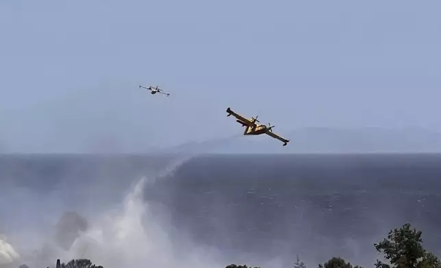 Firefighting planes drop water while battling a blaze in the seaside area of Palaia Fokaia, south of Athens, Thursday, June 26, 2025, as authorities evacuate five locations during Greece's first summer heatwave with temperatures nearing 40 degrees Celsius (104 Fahrenheit).(AP Photo/Giorgos Delveroudis)