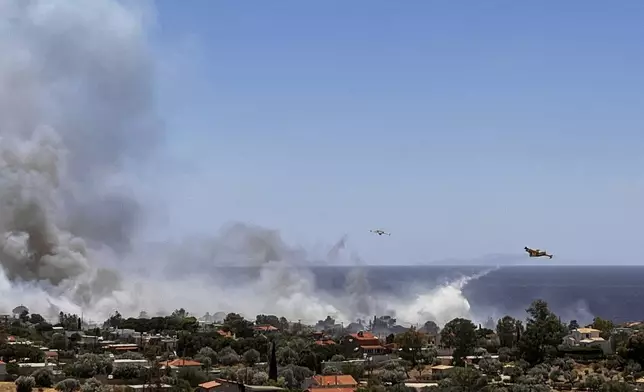 Firefighting planes drop water while battling a blaze in the seaside area of Palaia Fokaia, south of Athens, Thursday, June 26, 2025, as authorities evacuate five locations during Greece's first summer heatwave with temperatures nearing 40 degrees Celsius (104 Fahrenheit).(AP Photo/Giorgos Delveroudis)