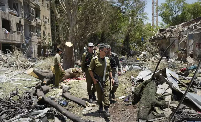 Israeli soldiers inspect the site struck by a direct missile strike launched from Iran in Tel Aviv, Israel, on Sunday, June 22, 2025. (AP Photo/Bernat Armangue)