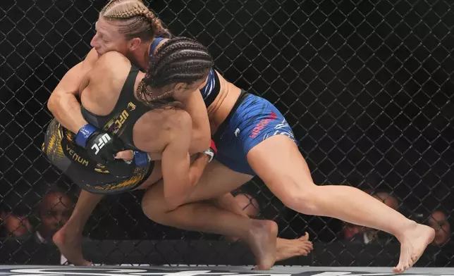 Kayla Harrison, right, grapples with with Julianna Peña during the first round of a women's bantamweight bout at the UFC 316 mixed martial arts event Sunday, June 8, 2025 in Newark, N.J. (AP Photo/Frank Franklin II)