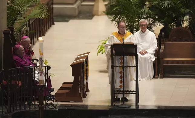 Father Dan Griffith, at podium, speaks as Archbishop Bernard Hebda, listens during funeral services for Mark and Melissa Hortman at the Basilica of St. Mary in Minneapolis, Minn., on Saturday, June 28, 2025. (Alex Kormann/Star Tribune via AP, Pool)