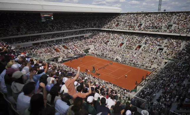 Spectators react as Italy's Jannik Sinner, left, prepares to serve against Spain's Carlos Alcaraz during their final match of the French Tennis Open at the Roland-Garros stadium in Paris, Sunday, June 8, 2025. (AP Photo/Thibault Camus)