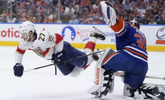 Florida Panthers center Eetu Luostarinen (27) trips over Edmonton Oilers goalie Calvin Pickard (30) during the first period in Game 5 of the NHL hockey Stanley Cup Final in Edmonton, Alberta, Saturday, June 14, 2025. (Darryl Dyck/The Canadian Press via AP)