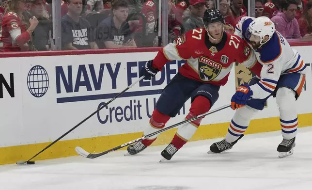 Florida Panthers center Eetu Luostarinen (27) defends against Edmonton Oilers defenseman Evan Bouchard (2) during overtime in Game 4 of the NHL hockey Stanley Cup Final Thursday, June 12, 2025, in Sunrise, Fla. (AP Photo/Lynne Sladky)