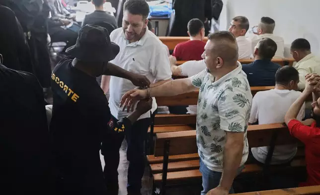 Colombians and Haitians accused of involvement in the 2021 assassination of Haitian President Jovenel Moise get their handcuffs removed in a court hearing in Port-au-Prince, Haiti, Monday, June 2, 2025. (AP Photo/Odelyn Joseph)