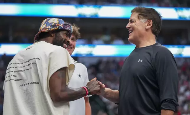 Dallas Mavericks' Kyrie Irving, left, talks with Mavericks minority owner Mark Cuban during the first half of a WNBA basketball game between the Dallas Wings and the Indiana Fever Friday, June 27, 2025, in Dallas. (AP Photo/Julio Cortez)