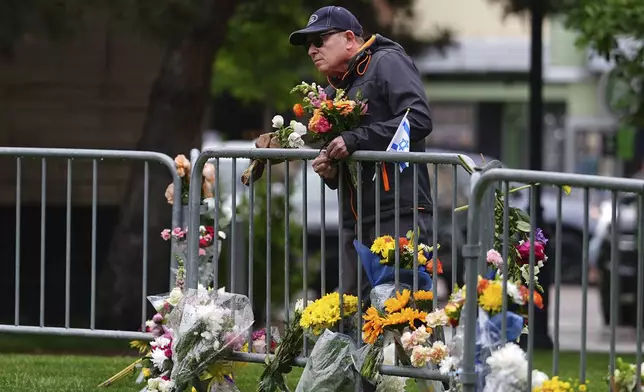 A man affixes a bouquet of flowers to a makeshift memorial for victims of an attack outside of the Boulder County, Colo., courthouse Tuesday, June 3, 2025, in Boulder, Colo. (AP Photo/David Zalubowski)