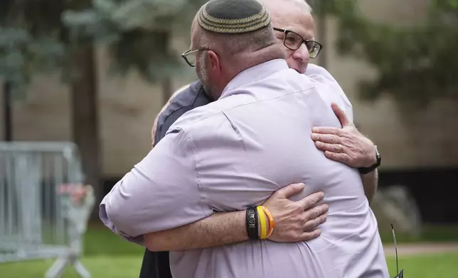 Rabbi Fred Greene of Congregation Har Hashem, front, hugs a man outside of the Boulder County, Colo., courthouse after Sunday's attack, Monday, June 2, 2025, in Boulder, Colo. (AP Photo/David Zalubowski)