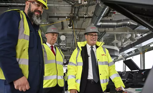 Britain's Prime Minister Keir Starmer, right, and Britain's Defence Secretary John Healey, center, speak to a member of staff during a visit to the BAE Systems'Govan facility, in Glasgow, Scotland, Monday June 2, 2025. (Andy Buchanan, Pool Photo via AP)