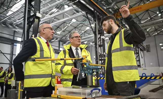 Britain's Prime Minister Keir Starmer, center, and Britain's Defence Secretary John Healey, left, speak to a member of staff during a visit to the BAE Systems'Govan facility, in Glasgow, Scotland, Monday June 2, 2025. (Andy Buchanan, Pool Photo via AP)