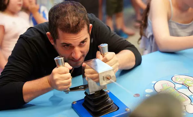 Park visitor Chris Del Borrello plays a water gun game at Playland's Castaway Cove amusement park, in Ocean City, N.J, on Friday, June 6, 2025. (AP Photo/Mingson Lau)