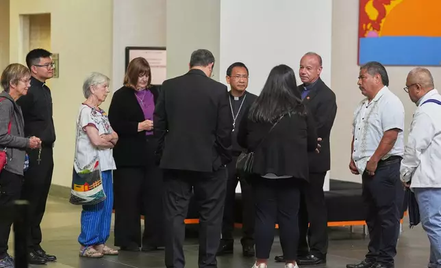 Bishop Michael Pham, center, leads an inter-faith group as they stand in the lobby of a federal building to be present during immigration hearings, Friday, June 20, 2025, in San Diego. (AP Photo/Gregory Bull)