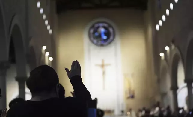 A woman prays during Mass before a group of interfaith leaders, led by Bishop Michael Pham, enter a federal building to be present during immigration hearings, Friday, June 20, 2025, in San Diego. (AP Photo/Gregory Bull)
